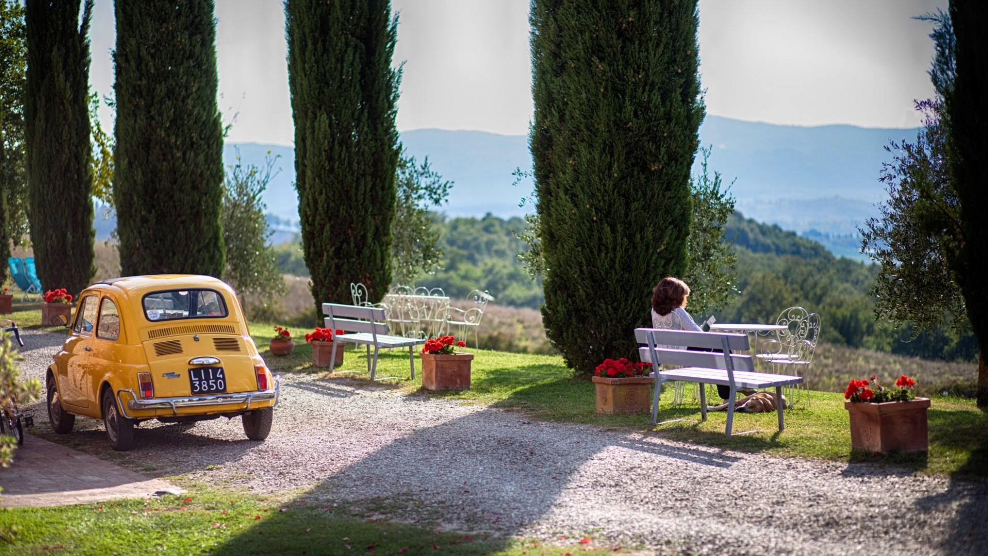 Toscaanse heuvels - cipressen - Fiat 500 - bankjes met lezende vrouw