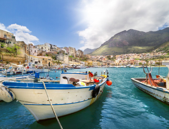 Ontdek wat er te doen is in Noordwest-Sicilië - vissersbootjes op de zee - San Vito La Capo in achtergrond