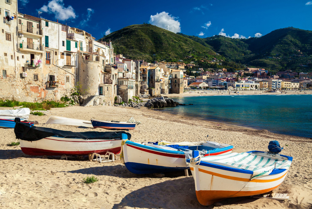 Sicilië - strand met vissersbootjes- stadje in achtergrond