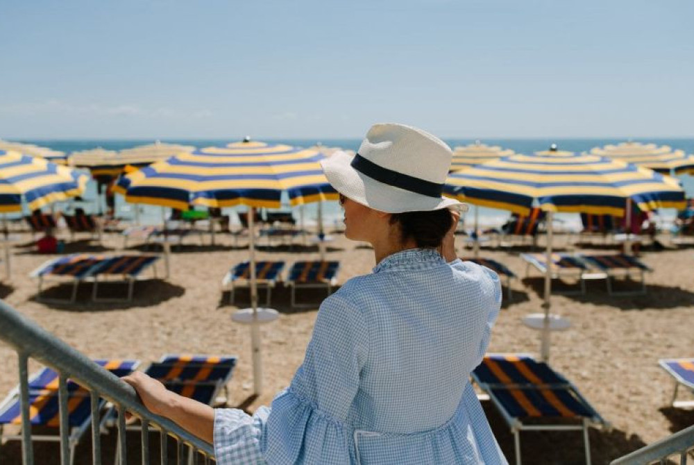 Strand vrouw met hoed bedjes en parasols le Marche Numana aan de oostkust van Italië