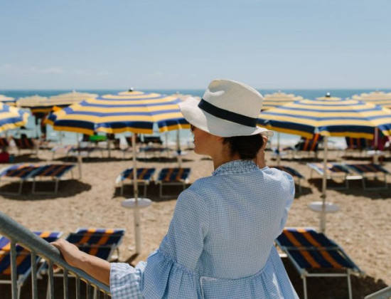 Strand vrouw met hoed bedjes en parasols le Marche Numana aan de oostkust van Italië